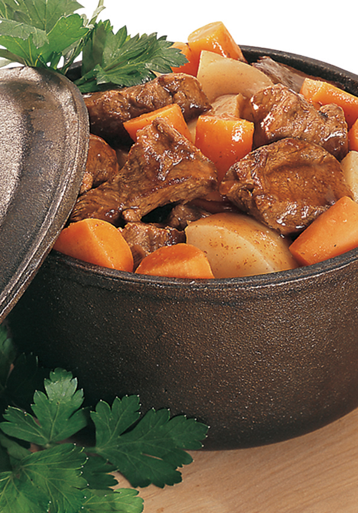 Wild boar stew in a cast iron pot with carrots and onions