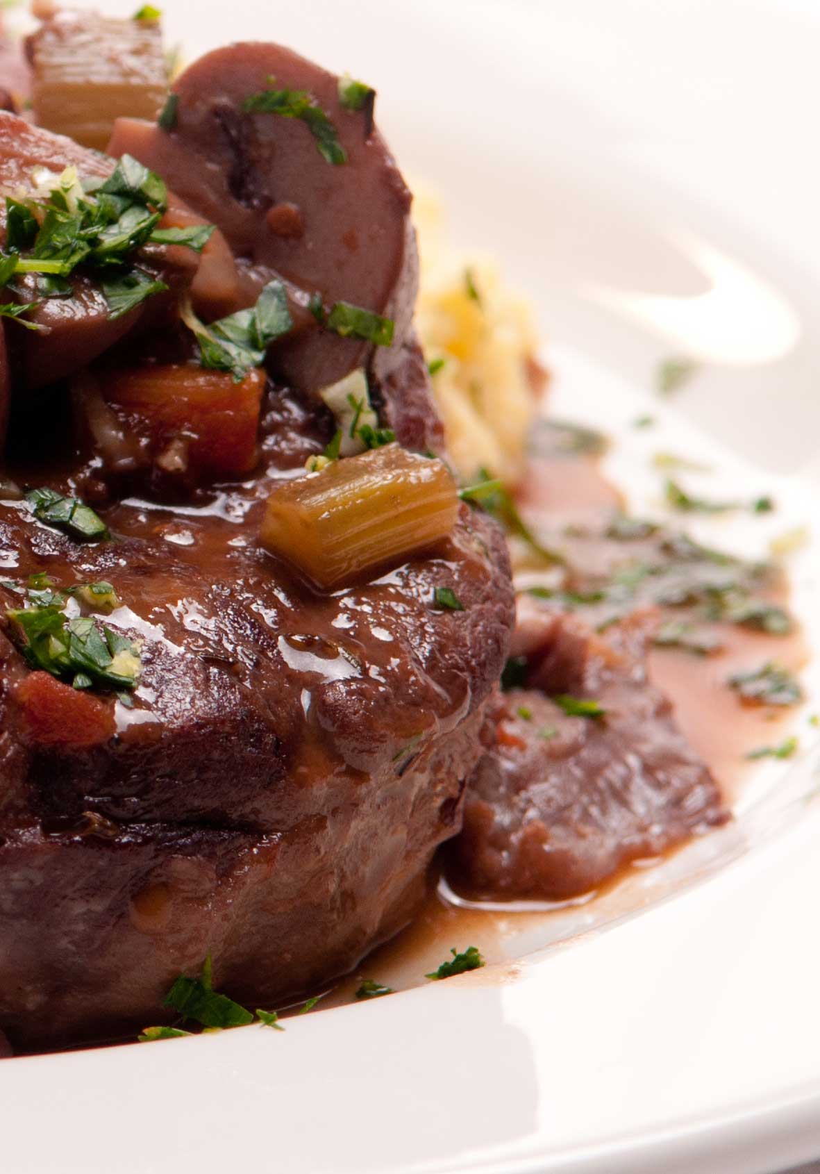 Osso Buco on a white plate with mushrooms