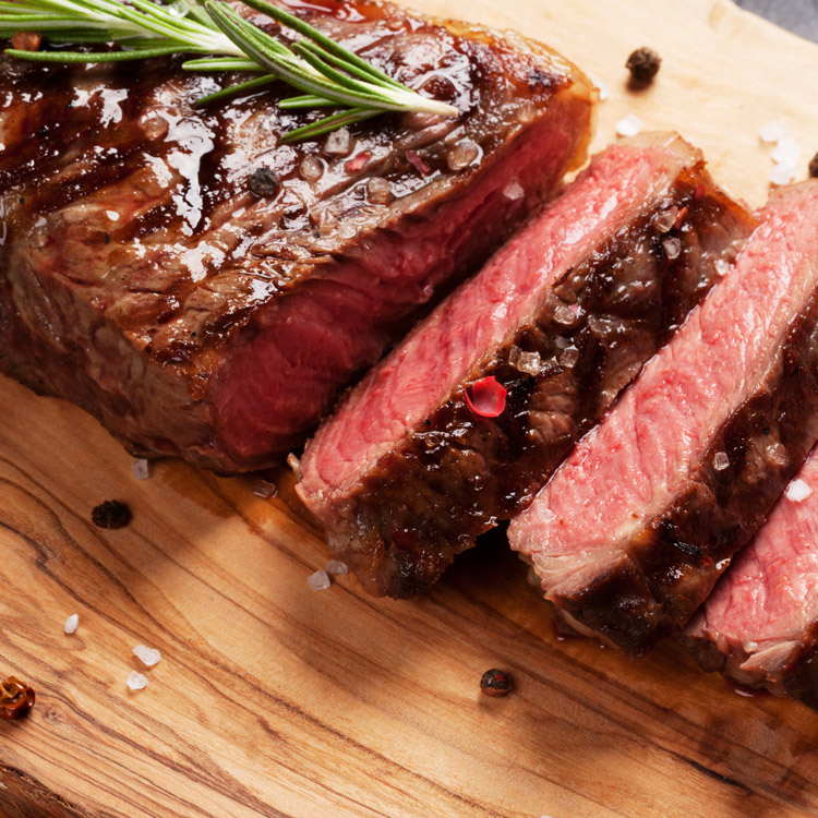 bison steak sliced with a sprig of rosemarey